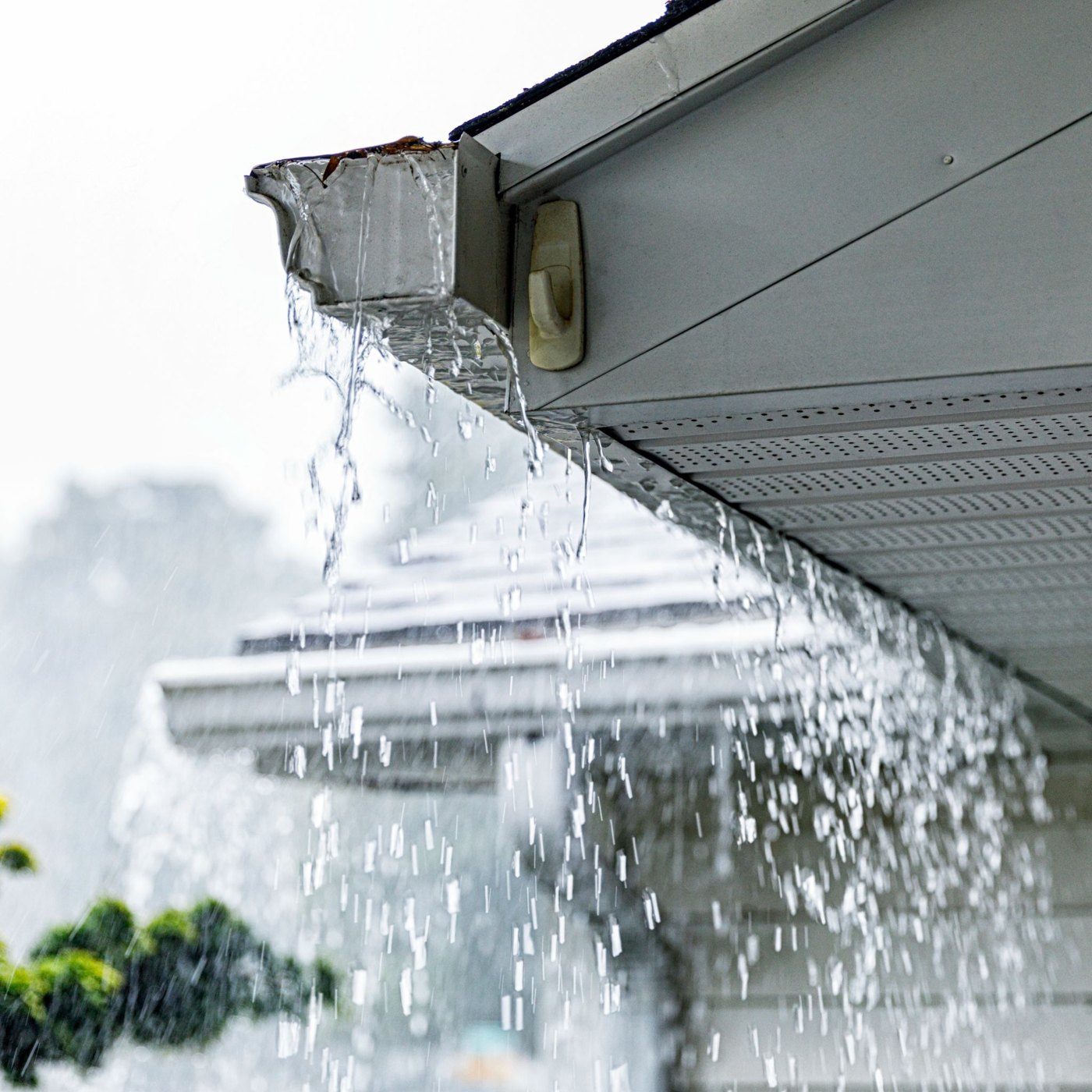 Rainwater overflowing a clogged gutter that needs cleaning