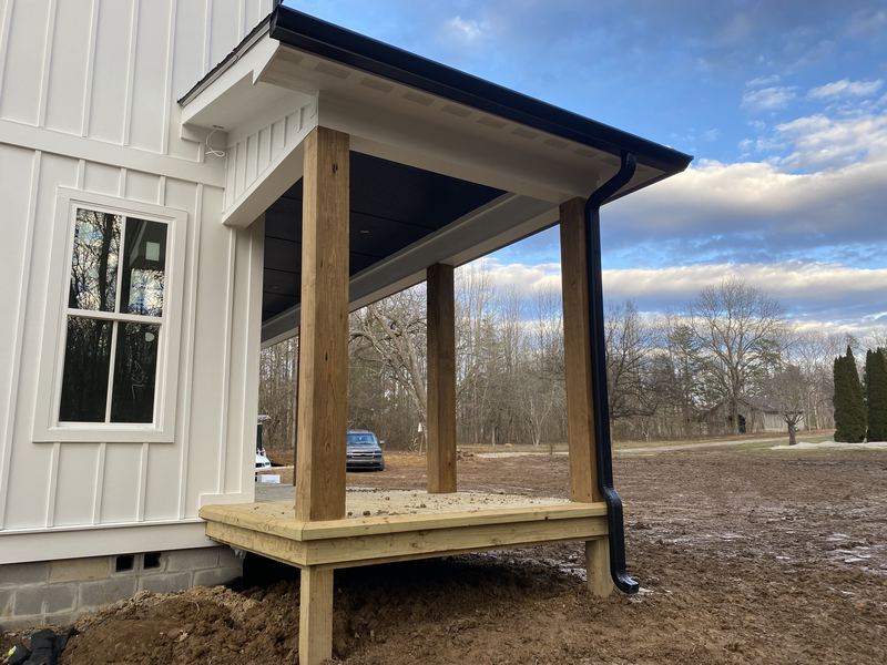 New porch addition with stone column and dark gutter run