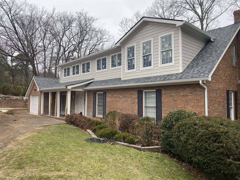 Two-story brick and siding home with white seamless gutters